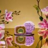 Mini Muscat Grape Sencha Snowskin mooncake by JU Signatures, whole and halved showing white lotus paste with a green sencha centre